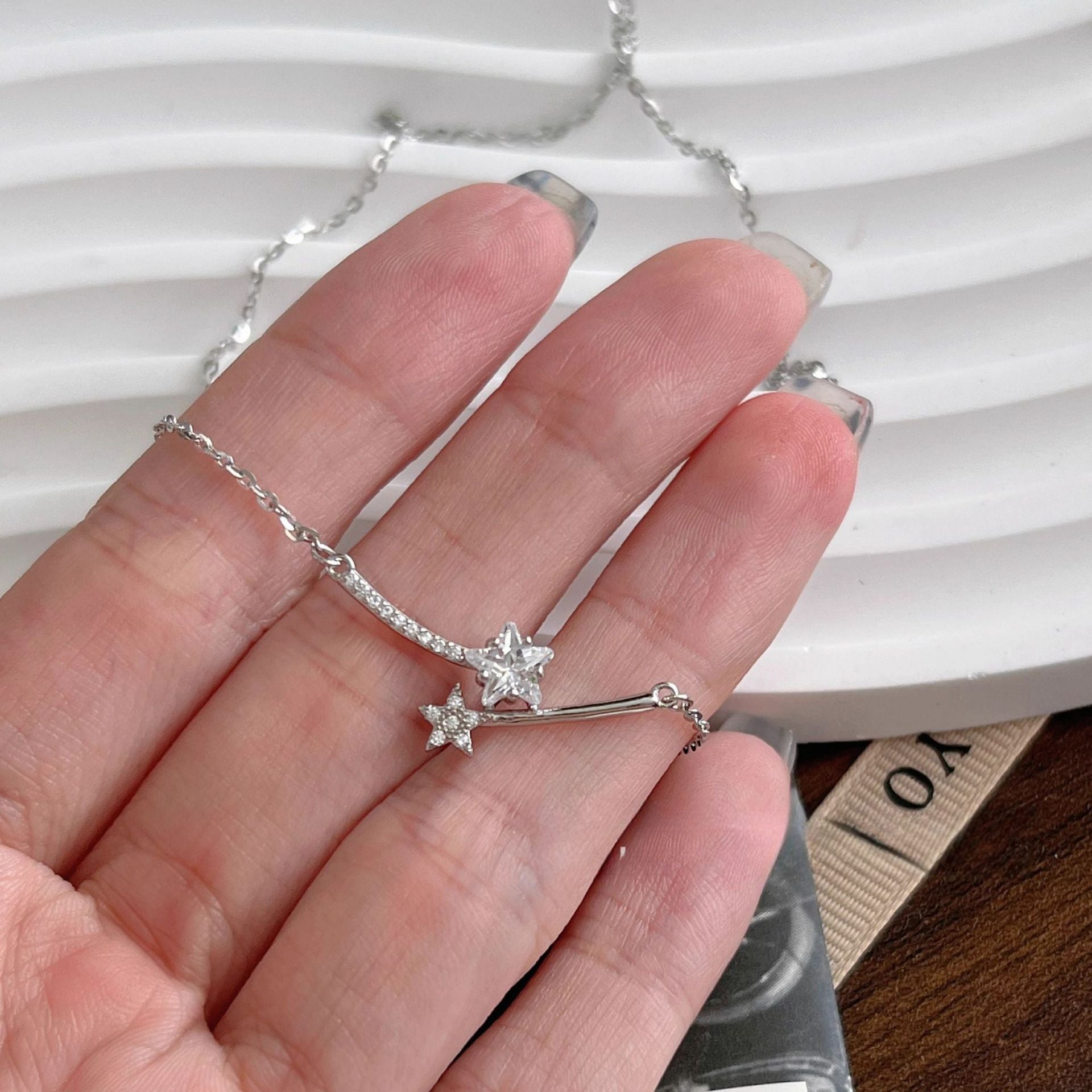 A hand holding a sterling silver star pendant to show its delicate size.