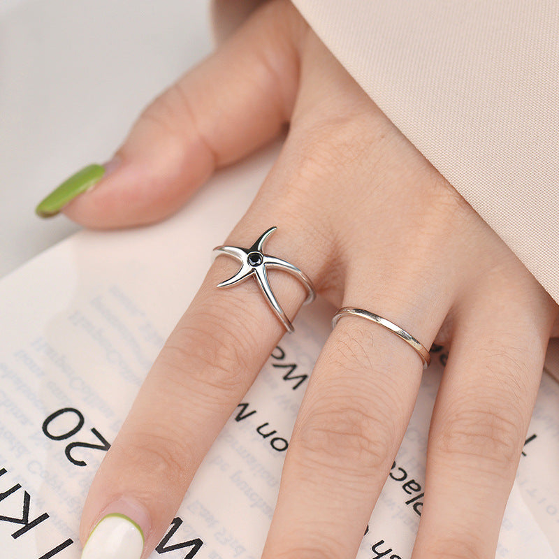 A hand modeling the sterling silver starfish ring alongside a simple band to show versatile styling options.