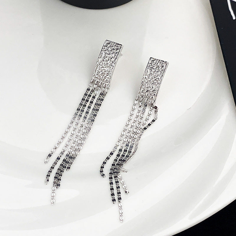 Detailed view of the sterling silver tassel earrings with textured rectangular top