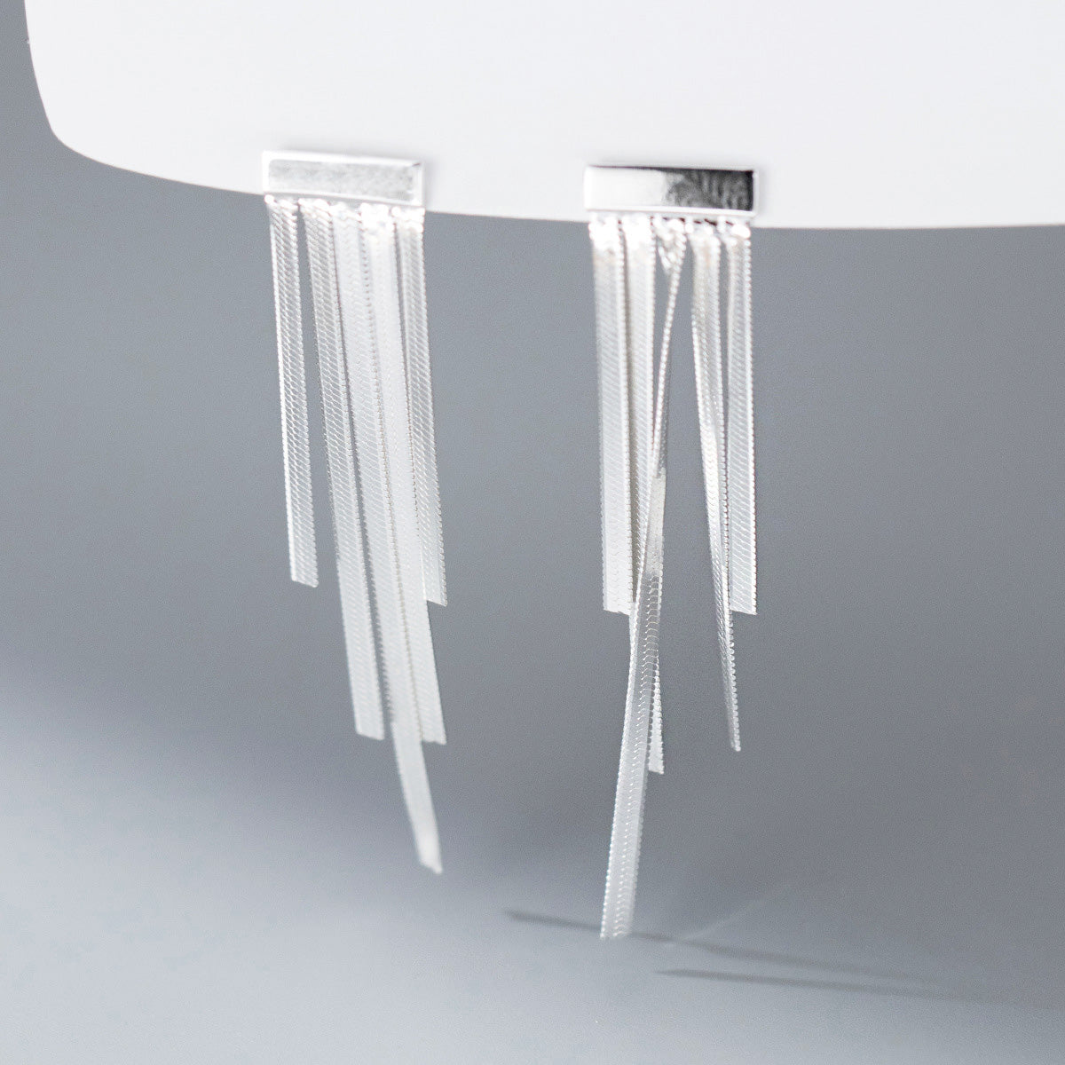 A pair of 925 sterling silver wide flat tassel drop earrings on a white background