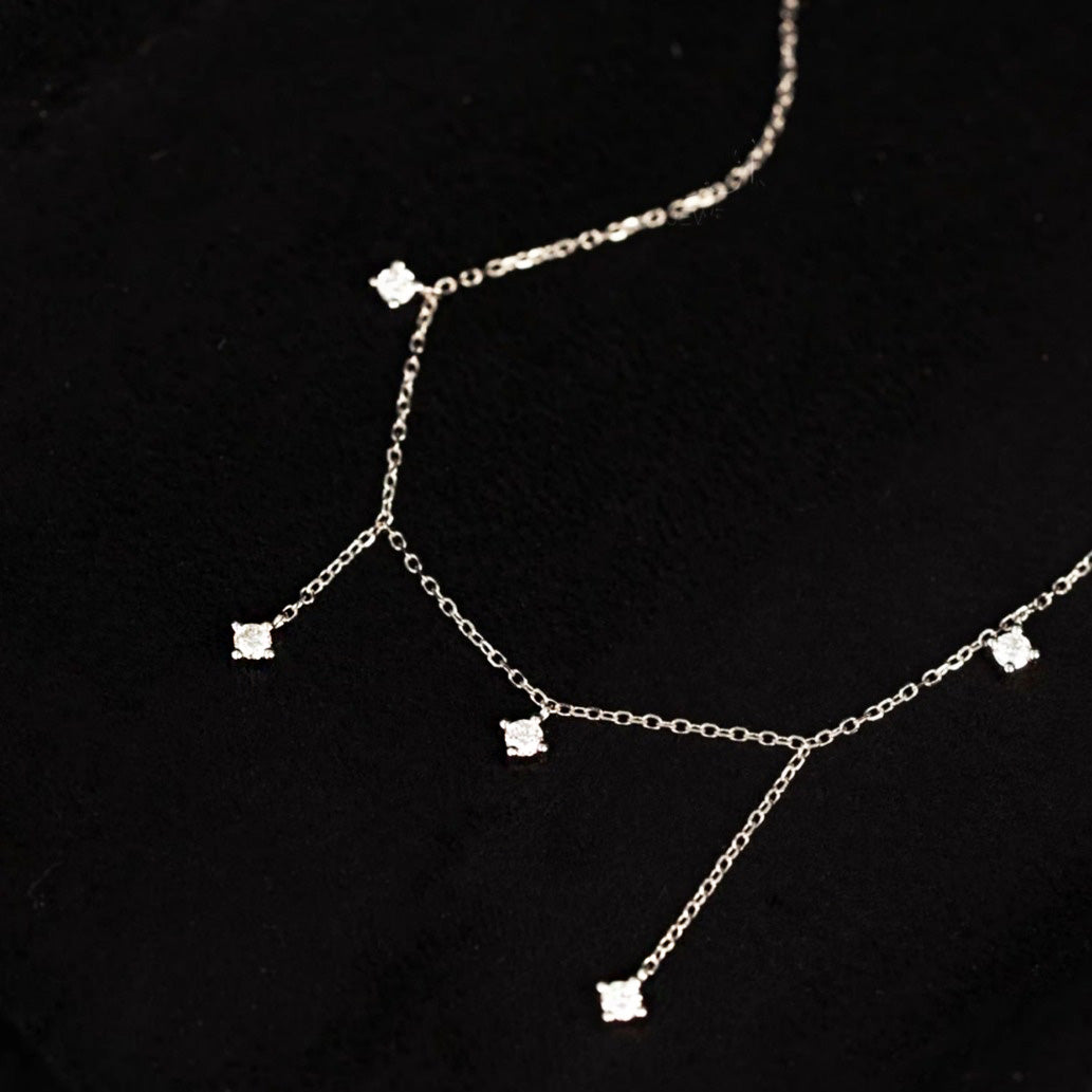 Close-up of a sterling silver necklace with five clear zircon stones