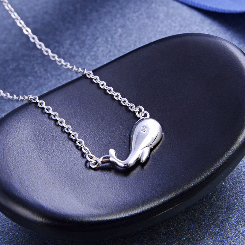 The silver whale necklace displayed elegantly on a black leather case.