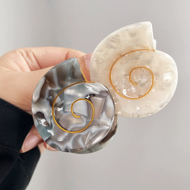 Detailed view of two conch shell hair clips with gold accents