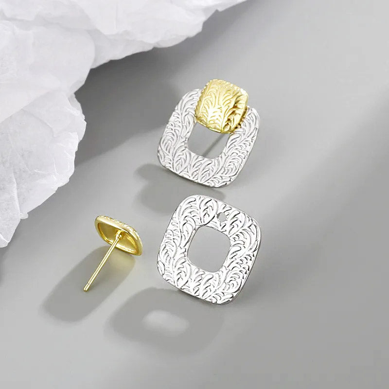 Detailed view of the two-tone geometric square earrings showcasing the engraved leaf pattern.