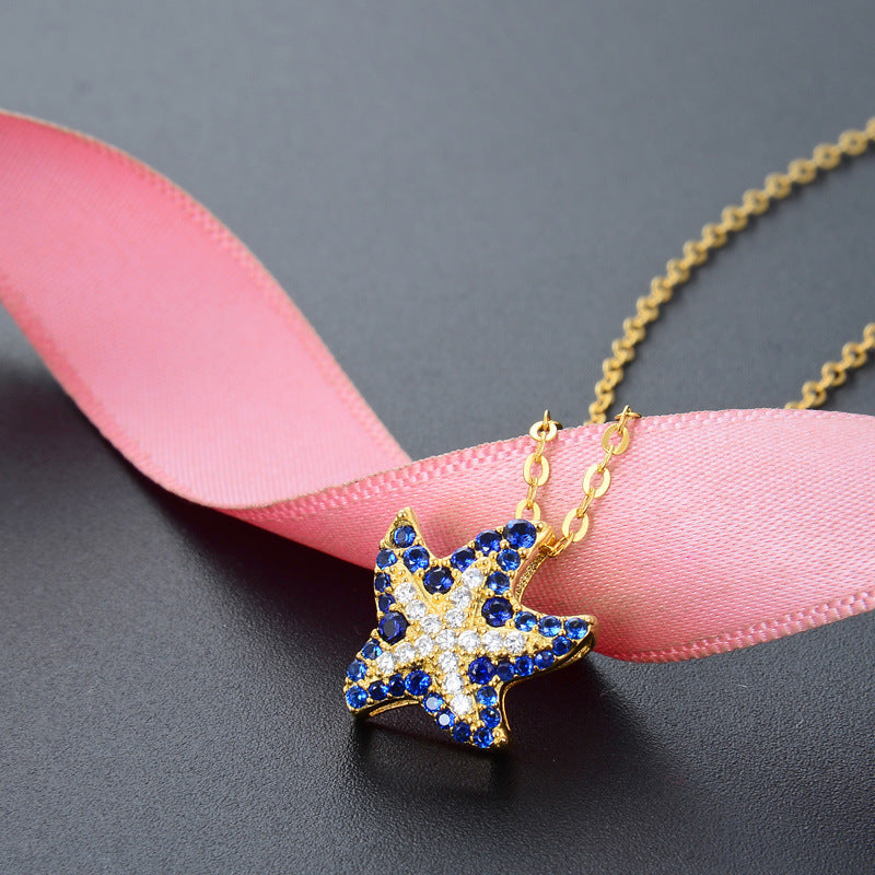 A detailed shot of the ocean sapphire starfish pendant on a pink ribbon.