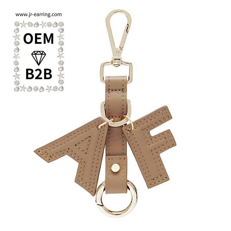 A tan leather keychain with TF initials and gold hardware