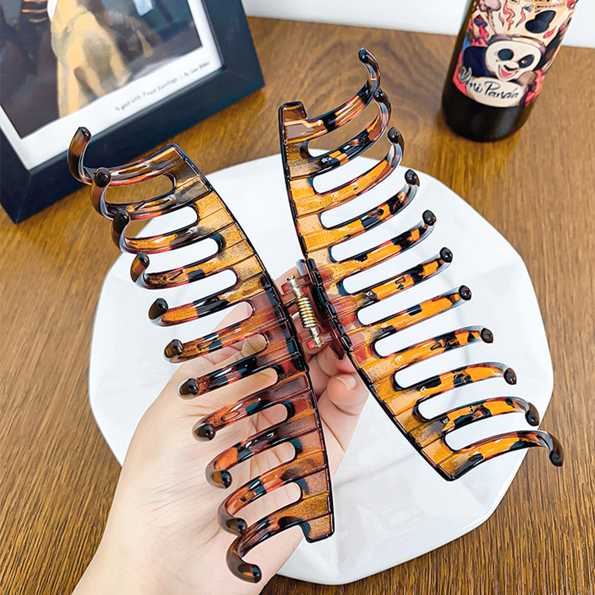 A hand holding a large tortoiseshell hair clip to show its size and strong grip
