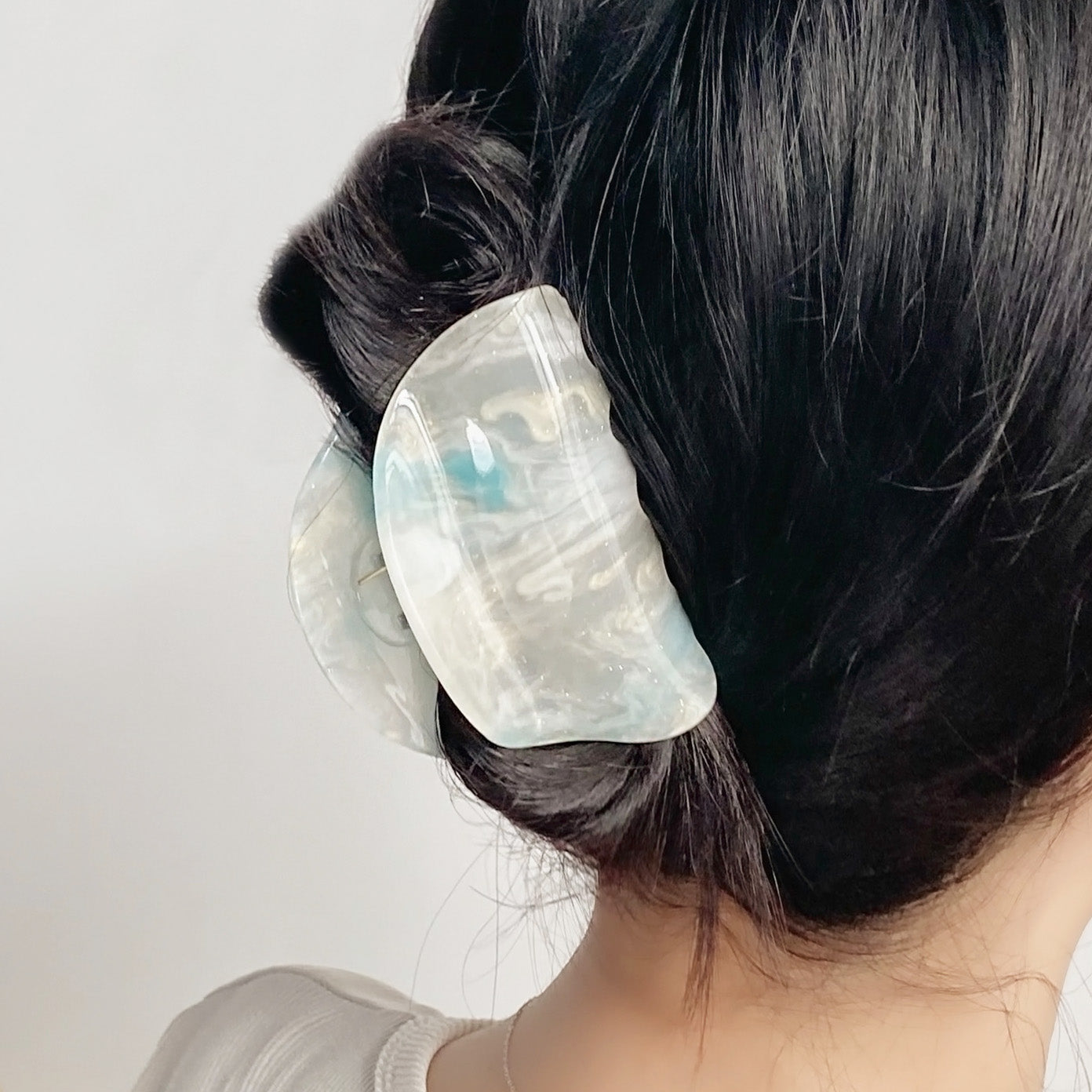 A model showcasing the elegant semicircle acetate hair claw in her bun.