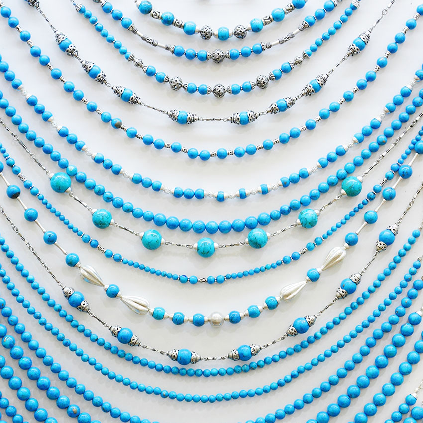 A collection of custom beaded necklaces in various styles and colors, including turquoise and pearl accents.