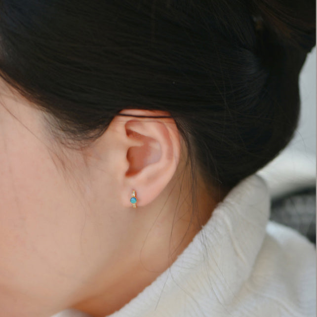 A model wearing the 7mm sterling silver opal hoop earring to show its scale.