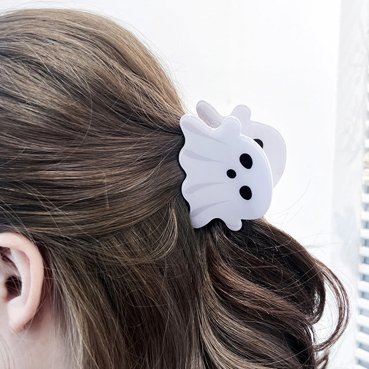A white ghost-shaped hair clip adding a fun Halloween accent to brown hair.