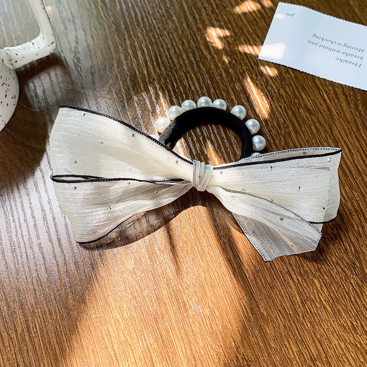 A beautiful white hair bow with intricate pearl details, showcasing the vintage style of the accessory set.