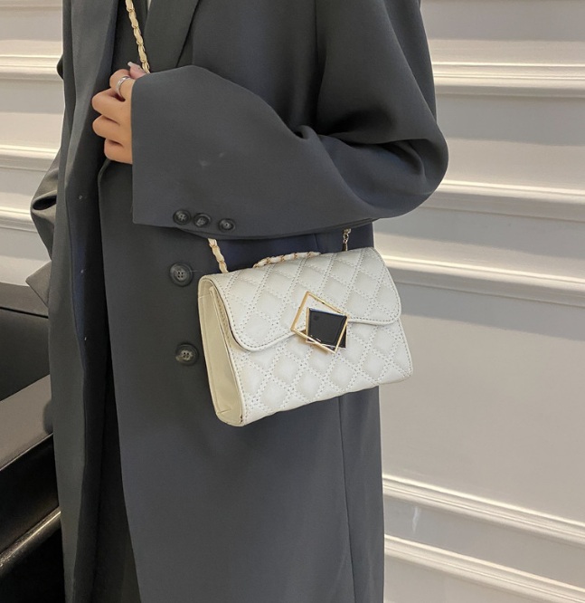 A model holding the white quilted purse, highlighting its elegant gold buckle and chain strap.
