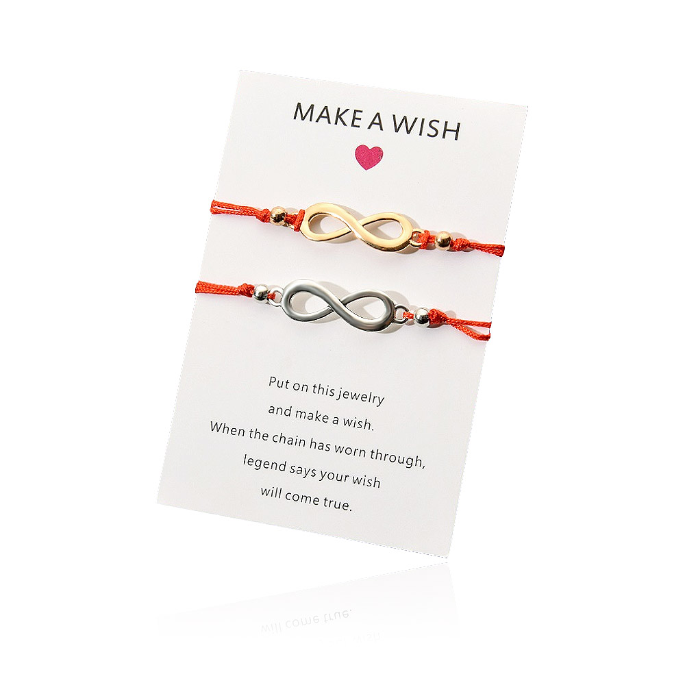 A pair of gold and silver infinity wish bracelets on a display card