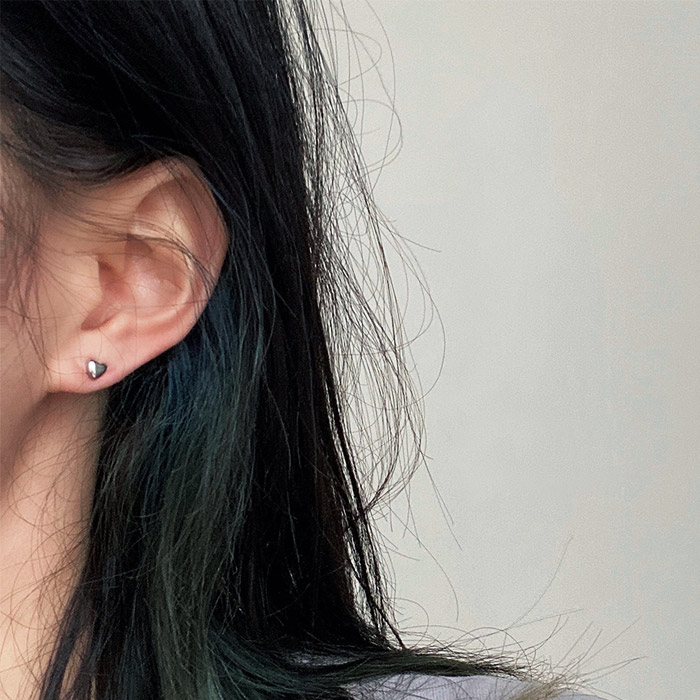 A model showcasing the Minimalist Tiny Heart Stud earring for size reference.
