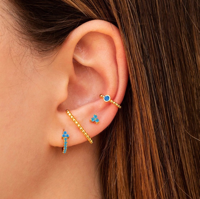 Model showcasing the versatile set of four gold and turquoise huggie earrings.