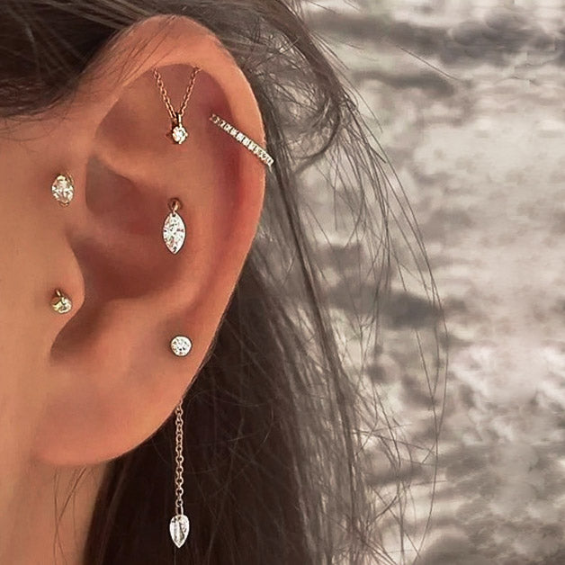 A model's ear adorned with the 925 sterling silver hidden helix tassel chain earrings in gold, showing a stylish layered effect.