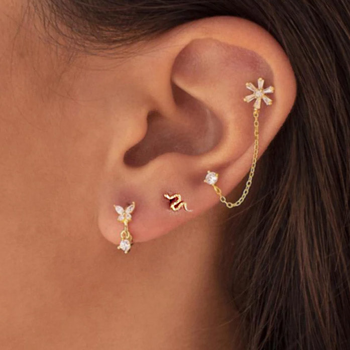 A model showcasing a curated ear with multiple sterling silver snake and zircon stud earrings.