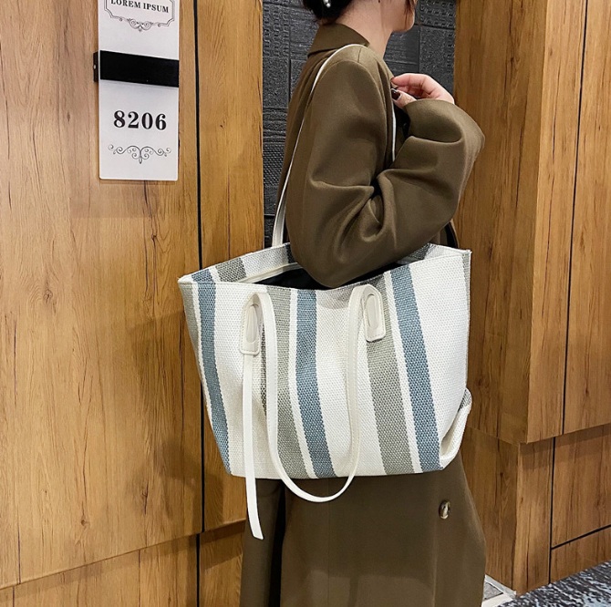 Woman holding a stylish and spacious striped canvas tote bag
