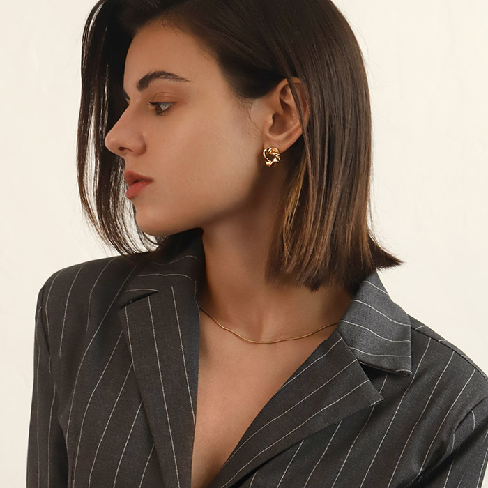A woman in a pinstripe blazer accessorizing with the Gold Triangle Post Earrings
