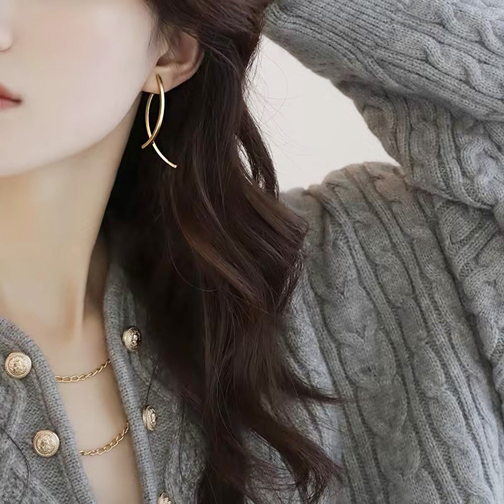 A woman wearing the elegant gold-plated fish shape wire cross clip-on earrings.