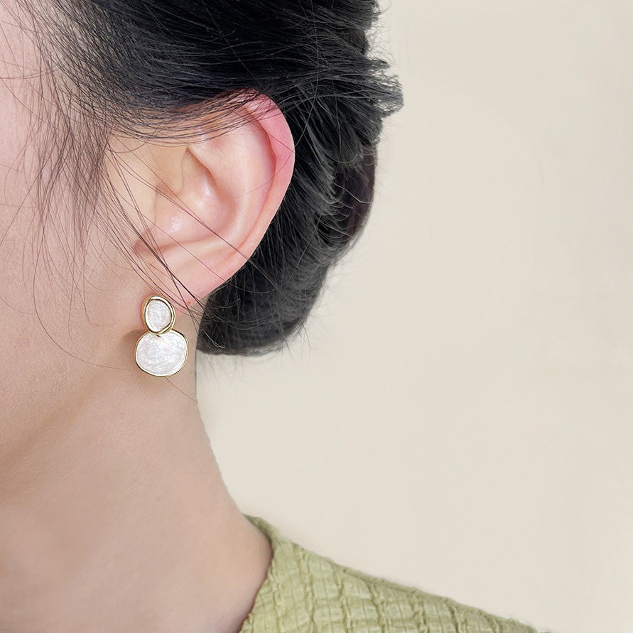 A woman models the chic 14k gold-plated cream-white enamel circle drop earrings.