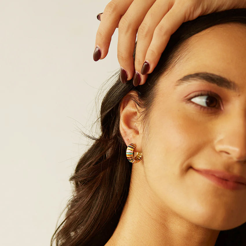 A model showcases the stylish look of the enamel rainbow chunky hoop earrings.