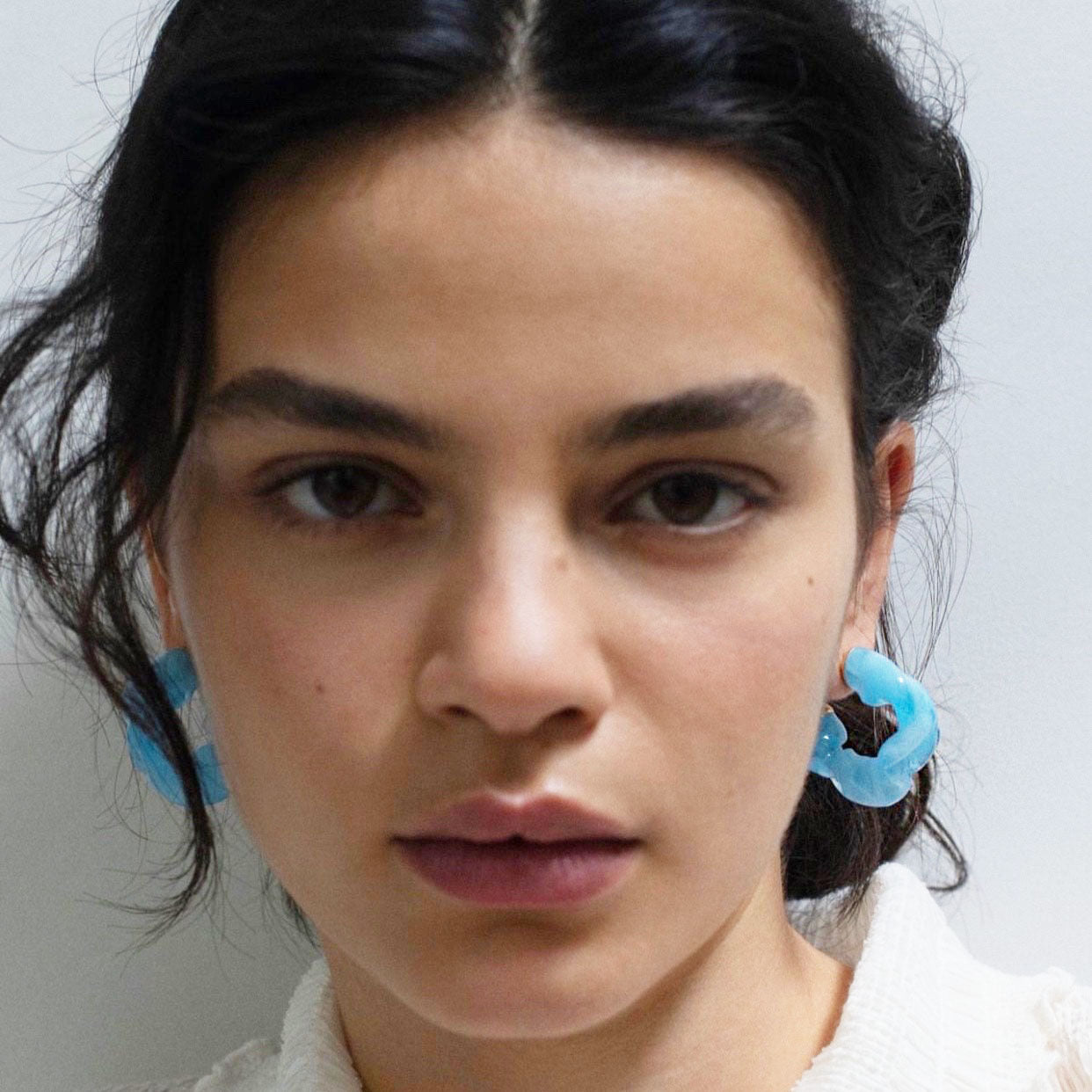 A model wears the light blue ruffle resin earrings, highlighting their stylish appeal.