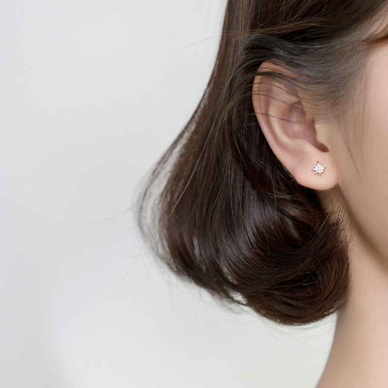 A woman wearing the delicate silver starburst stud earring to showcase its size and sparkle.