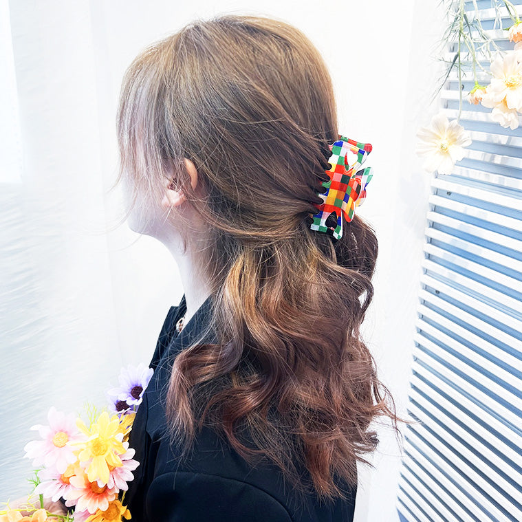 A woman with a colorful checkered hair clip in her hair, complemented by flowers.