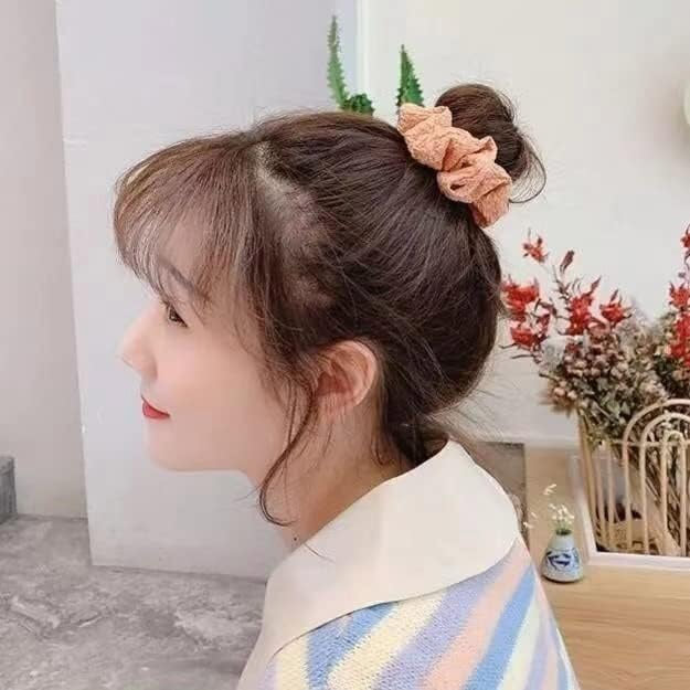 A pink scrunchie holding a neat hair bun.