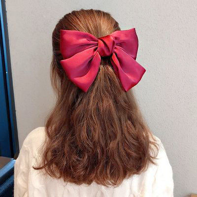 A model showcasing the sweet and cute style of a large red bow hair clip.
