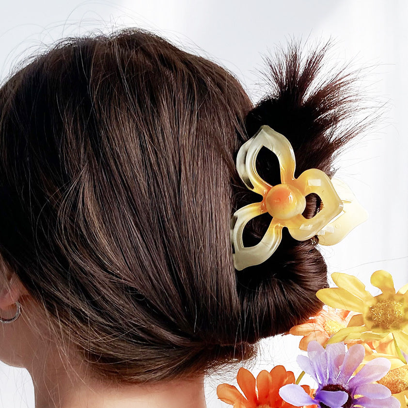 A yellow plumeria flower hair clip elegantly holding a hair bun