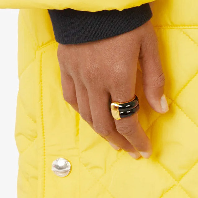 A model wearing the French-style enamel rings, complementing a stylish yellow quilted jacket.