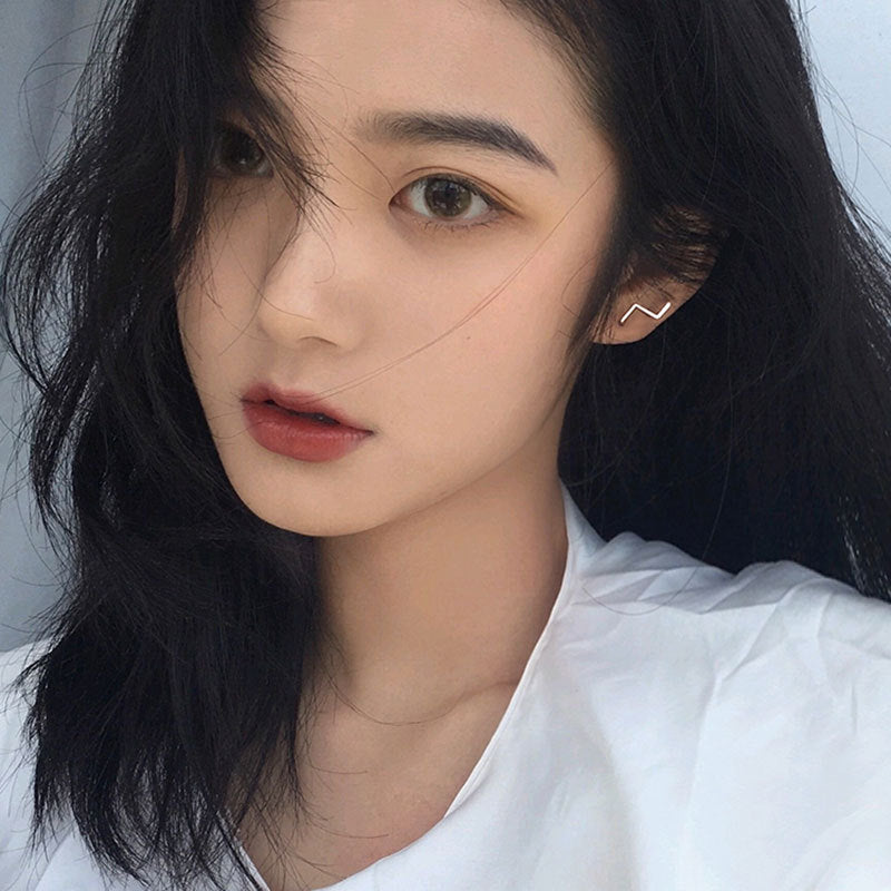 Model wearing the simple wave stud earring to showcase its subtle elegance.